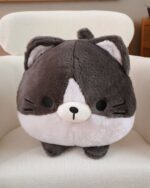 Close-up of a kawaii neko cat pillow, a soft, round plushie with black and white details.