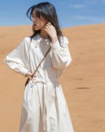 Woman wearing a beige korean style dress in a desert landscape.