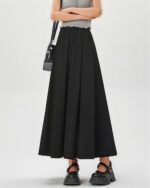 Long black korean aesthetic skirt, flowing design, worn by a woman.