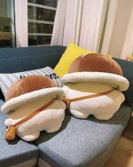 Mushroom homunculus plushie resting on a couch with pillows.
