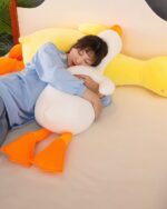 Waddles and Puddles goose plush toy with orange feet, resting on a bed.