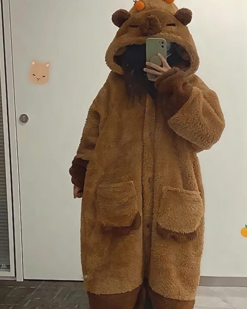 Person wearing a brown Capyvara Hooded Coat, a plush animal-themed hoodie.