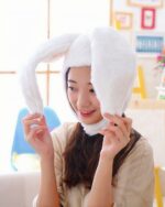 A white kawaii bunny ears hat being held by a person indoors.