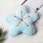 Blue sakura flower pillow with embroidered details and orange accents.