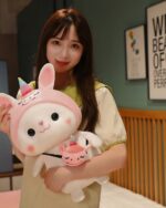 Close-up of a pink kawaii bunny plushie with a unicorn, holding another smaller plushie.