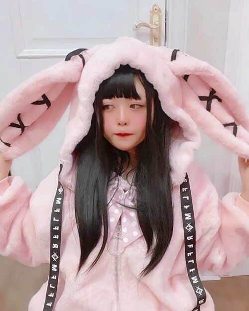 Person wearing a pink winter rabbit ears coat with embellishments.