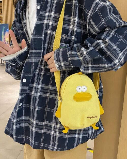 Yellow cartoon messenger bag with a duck design, held by a person.