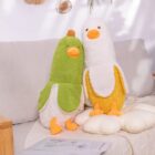 Two yellow and green banana duck plushies cuddle on a sofa.