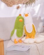 Two yellow and green banana duck plushies cuddle on a sofa.