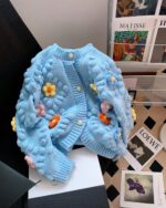 Light blue handmade aesthetic cardigan with crocheted flower details and button closures.
