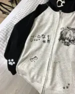 Close-up of a gray animecore cardigan hoodie featuring black accents, paw prints, and Japanese text.