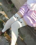 White kaomoji stockings with cute face print on a woman's legs.