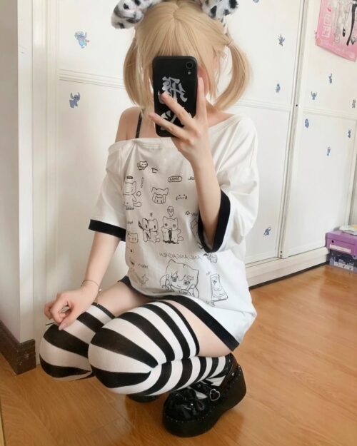 Close-up of a white harajuku kawaii t-shirt with cartoon designs and black striped leggings.