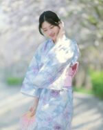 A woman wearing a pastel japanese yukata with floral print, outdoors.