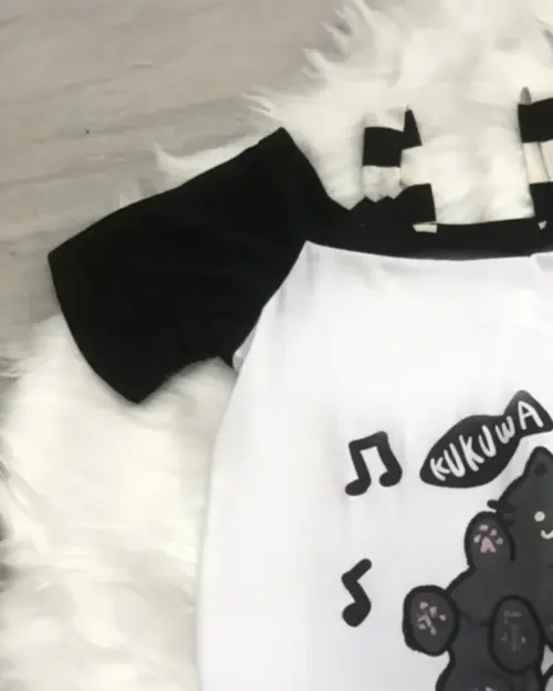 White t-shirt with a playful neko cat design and musical notes, a neko cat t-shirt.