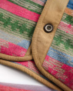 Close-up of a vintage aesthetic jacket featuring a colorful, striped wool design and button closure.