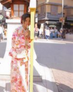 A woman wearing a pink japanese yukata in a Japanese street setting.