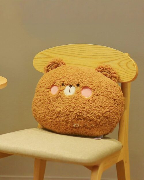 Kawaii animal plushie cushion on a wooden chair, soft and round design.