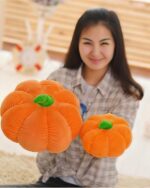 Two orange pumpkin plush cushions displayed by a woman, aesthetic room decor.