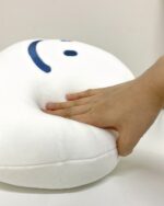 Close-up of a white fluffy happy cloud plushie with blue eyes and a soft texture.