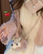 Close-up of a beige lolita french dress with ruffles, paired with a pink cardigan and accessories.