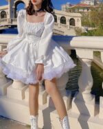 White french aesthetic dress with lace details and ruffles, outdoors.