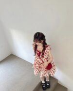 Girl wearing a lolita apple dress with cherry print, red ribbon, and black boots.