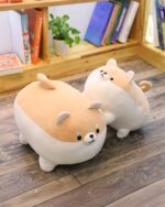 Two plush shibas, a super fat shiba plushie and another, displayed on a wooden floor.