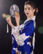 A blue and white satin japanese kimono with floral embroidery, featuring a model holding a fan.