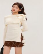 Cream off-shoulder kawaii aesthetic sweater featuring a bow detail and long sleeves.