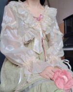 Close-up of a fairycore sleeve bow attached to a light pink dress, kawaii clothes style.