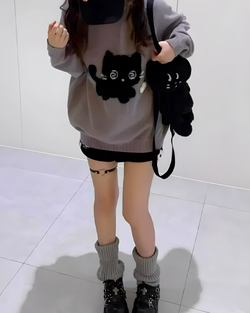 Woman wearing a Black Neko Sweater with a cat graphic, layered with accessories.