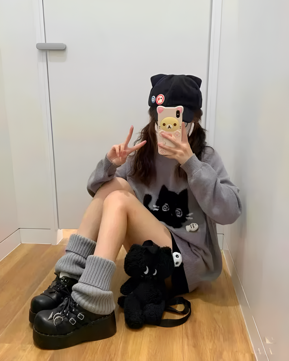 Woman wearing a Black Neko Sweater, beanie, and socks with a phone selfie.