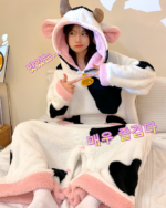 A woman wearing a black and white Cow Onesie - Kawaii Pajamas with a hood and heart details.