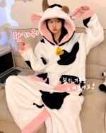 Pink and black Cow Onesie - Kawaii Pajamas featuring a hood and ears, shown in a bedroom setting.