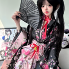 Woman wearing a Floral Short Yukata, featuring a black and floral pattern with pink accents and a fan.