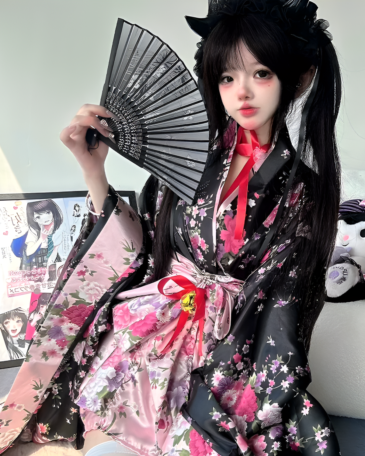 Woman wearing a Floral Short Yukata, featuring a black and floral pattern with pink accents and a fan.