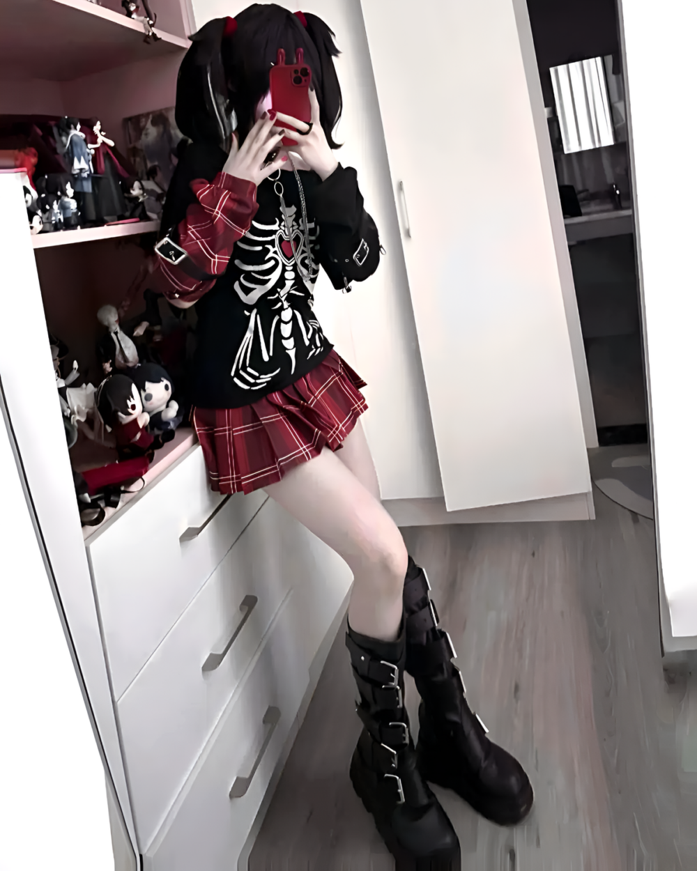 Person wearing a Needy Girl Overdose T-Shirt with a skeleton graphic, paired with a plaid skirt and boots.