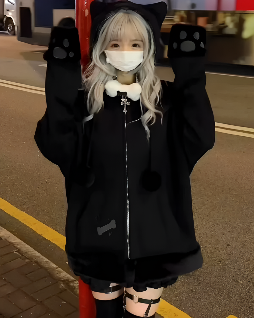 Person wearing a Neko Paw Hoodie with cat paw sleeves on a nighttime street.