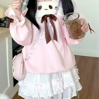 A person wearing a pink Neko Sweatshirt with a layered skirt and bow.