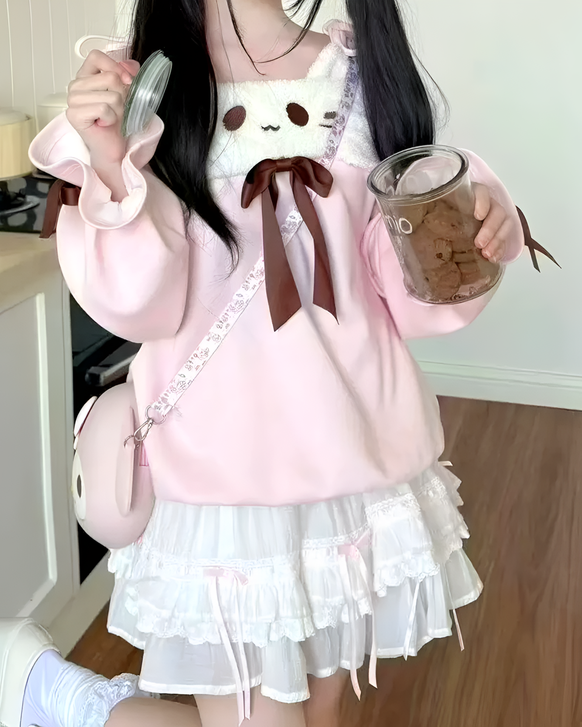 A person wearing a pink Neko Sweatshirt with a layered skirt and bow.