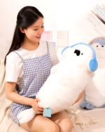 A white Kawaii Seal Plushie is held by a woman, with a blue ear and eye detail.