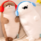 Two plush toys: a brown Kawaii Seal Plushie and a white otter with headphones, displayed on a textured blanket.