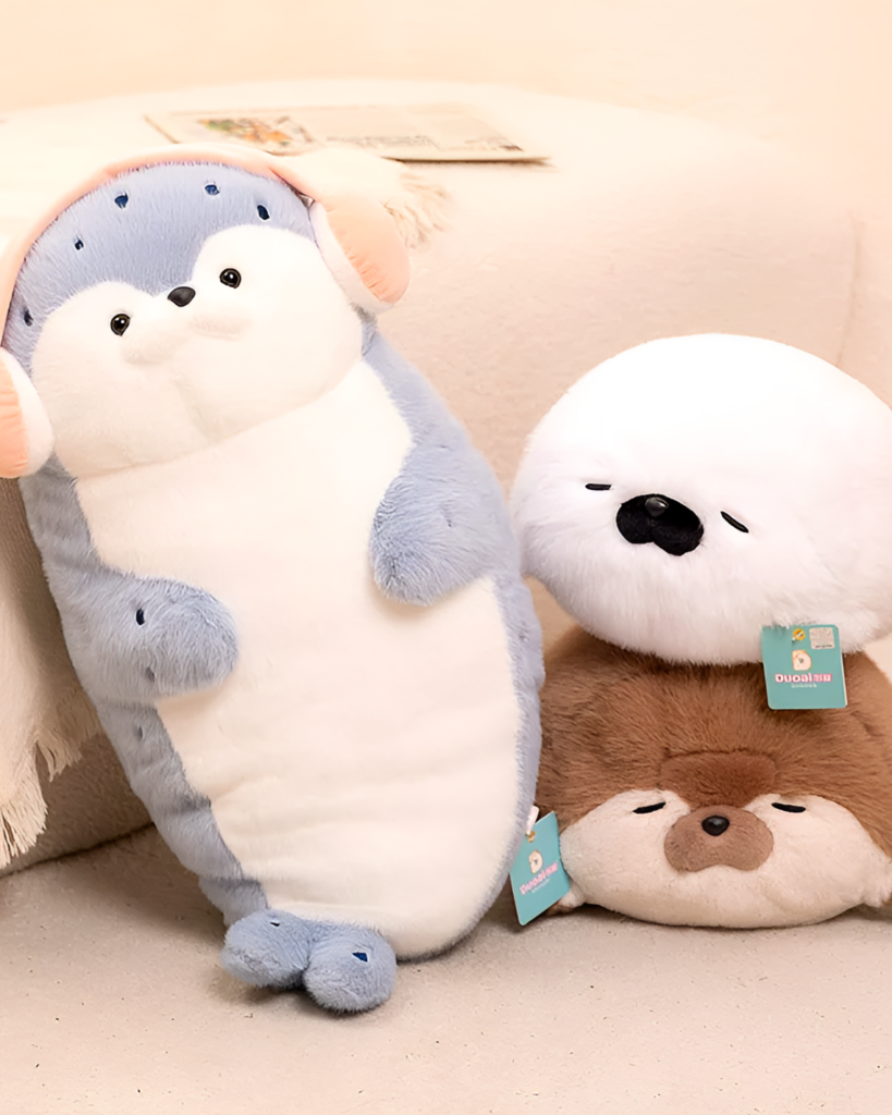 Two Kawaii Seal Plushies, one gray and one brown, displayed on a light beige surface.