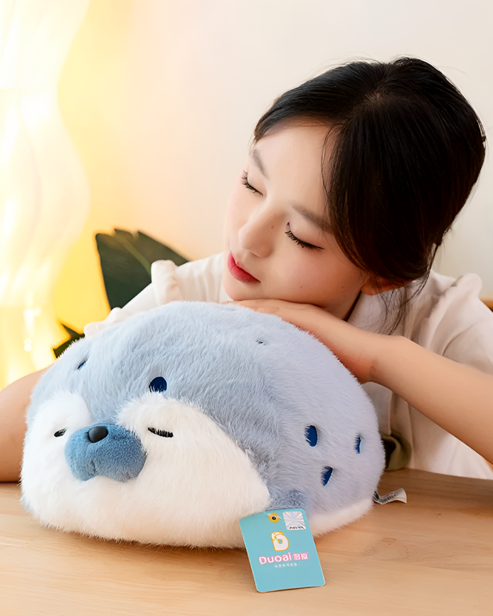 A Kawaii Seal Plushie, a soft, grey stuffed animal held by a person.