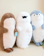 Three Kawaii Seal Plushies in brown, white, and blue colors stand side-by-side.