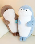 Two Kawaii Seal Plushies, one brown and one blue, displayed on a white pillow.