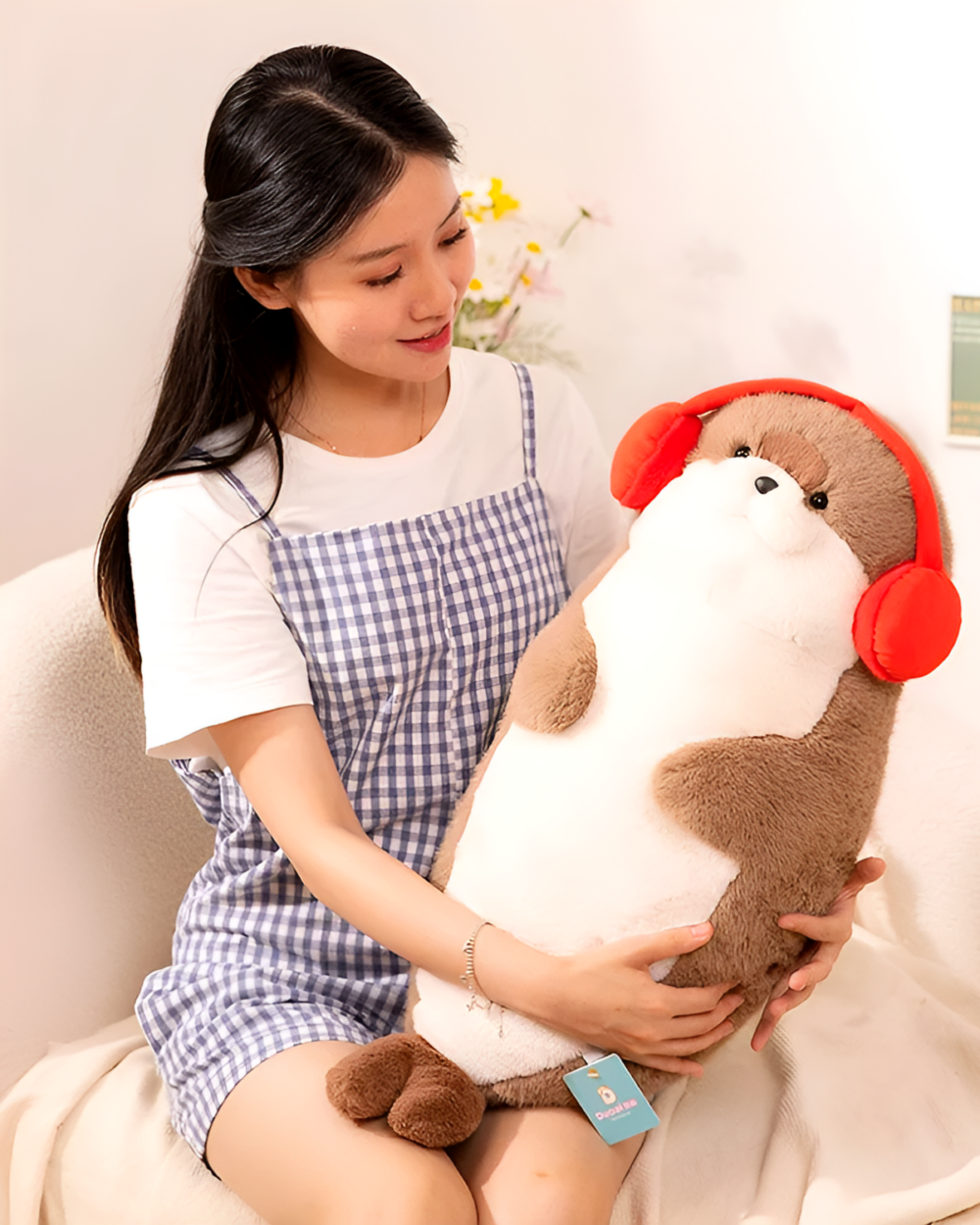 A Kawaii Seal Plushie, brown and white, with red headphones, held by a woman.