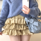 Yume Kawaii Aesthetic ruffled mini skirt in a light beige color, styled with a blue sweater and handbag.