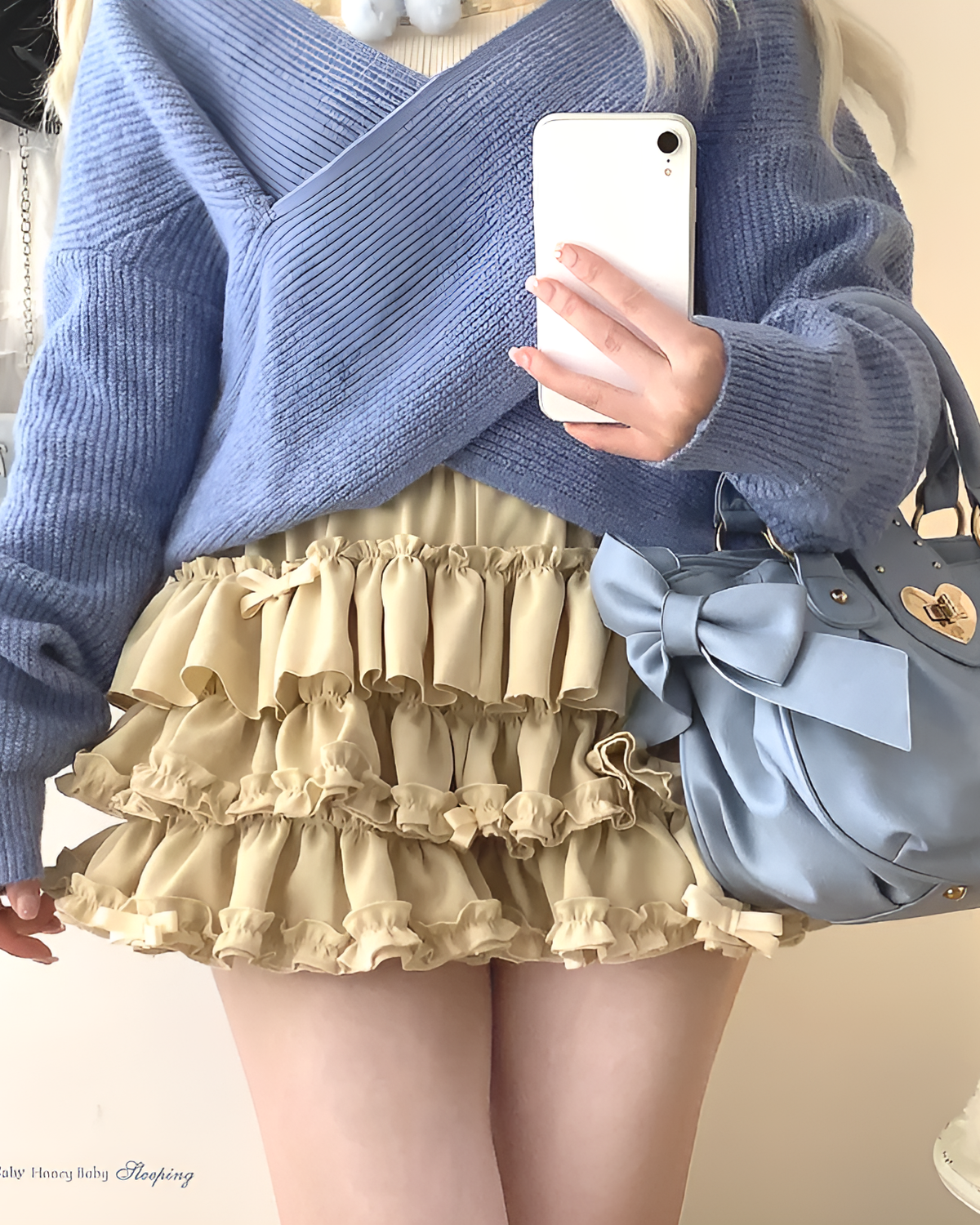 Yume Kawaii Aesthetic ruffled mini skirt in a light beige color, styled with a blue sweater and handbag.